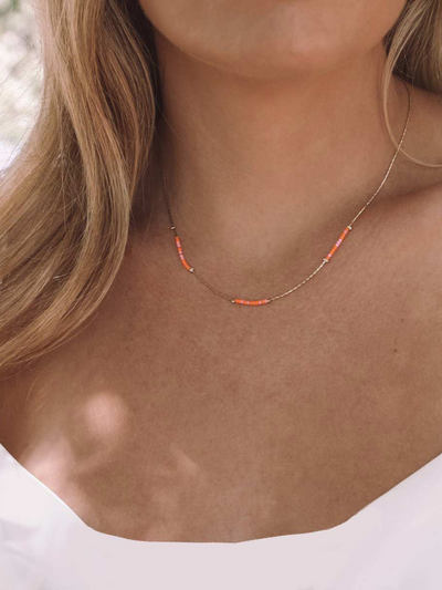 GIRL WEARING GOLD AND ORANGE NECKLACE