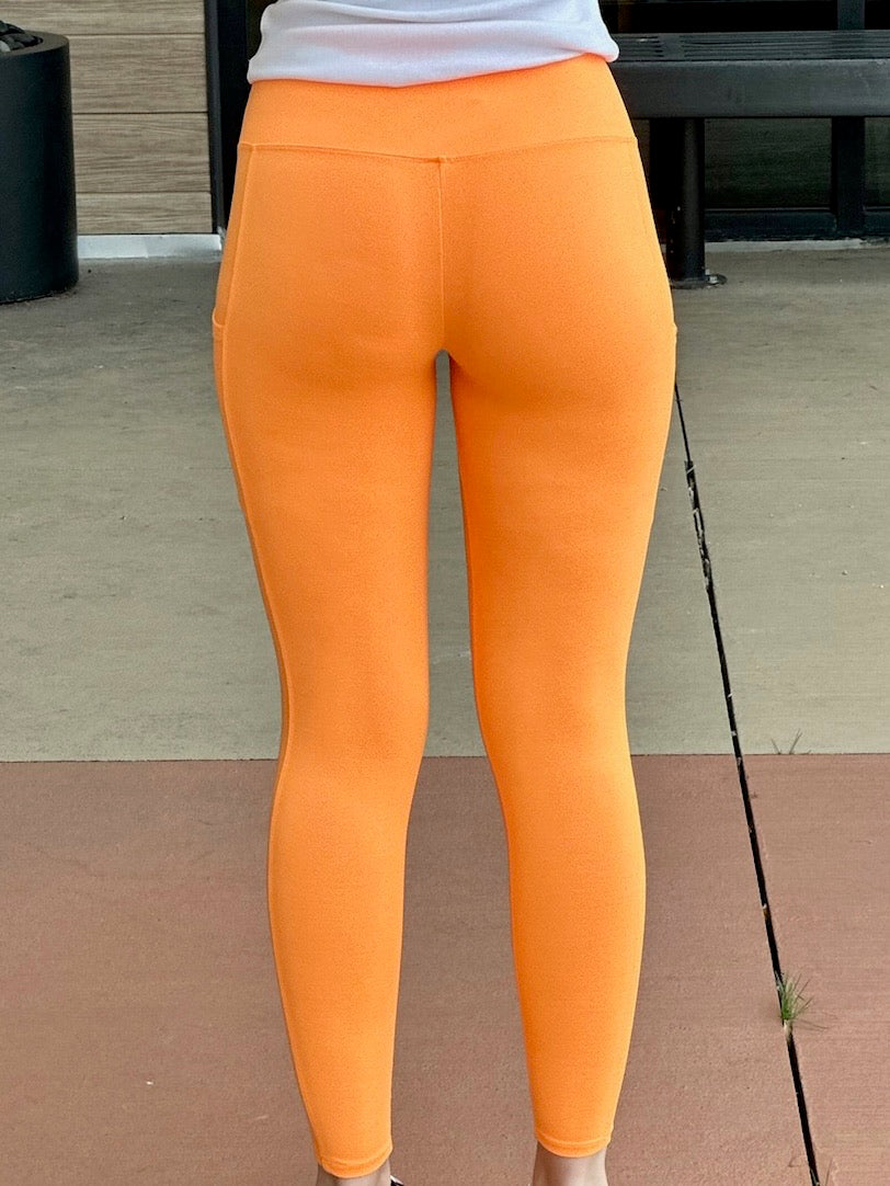 Megan in bright orange leggings back view