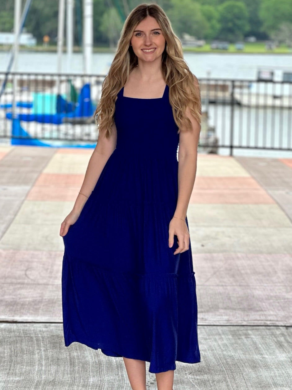 Lexi in bright blue midi dress front view one hand down and one hand holding dress