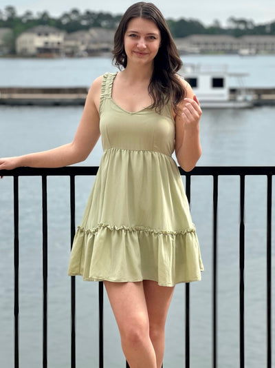 Megan in olive dress front view smiling holding hiar