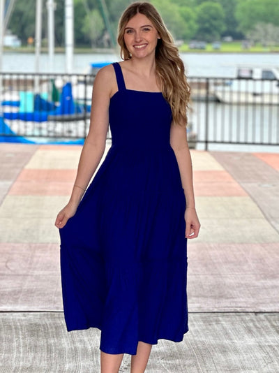 Lexi in bright blue midi dress holding dress