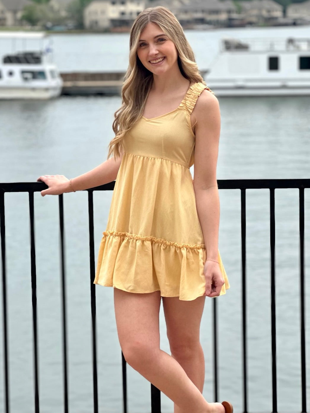 Lexi in yellow dress smiling holding dress