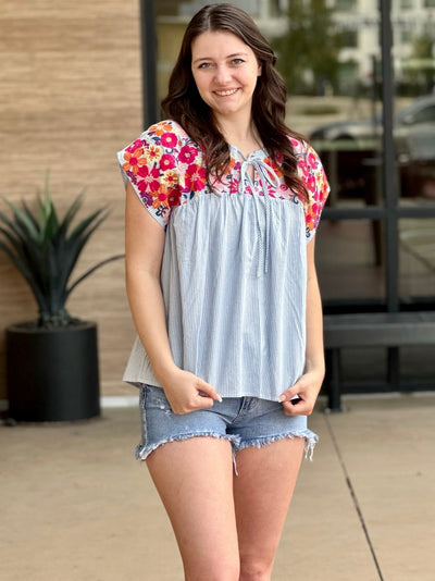 Megan in denim ruffle sleeve top front view shoulder popped smiling