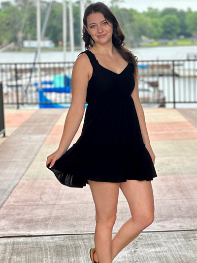 Megan in black dress smiling and holding dress
