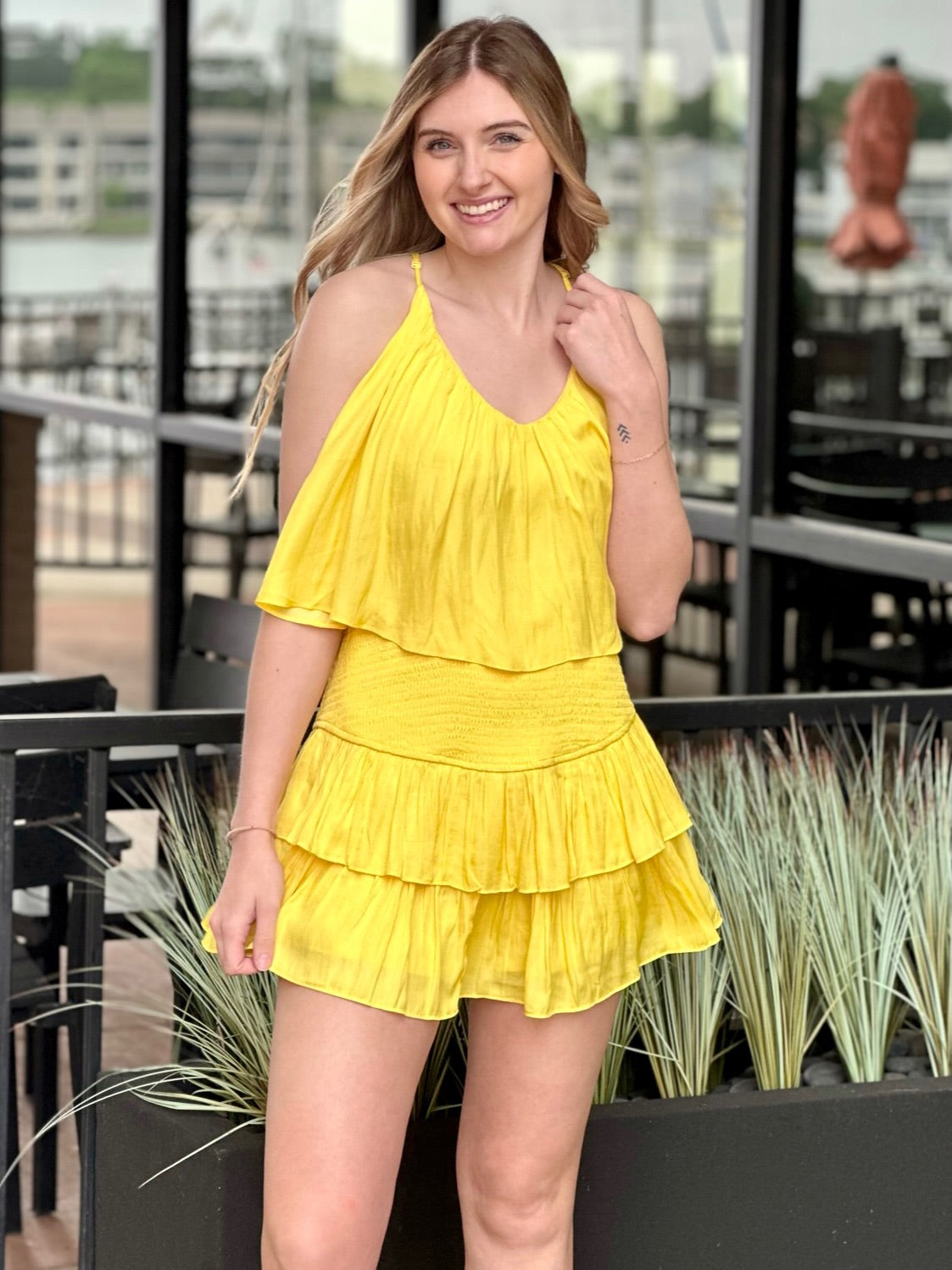 Lexi in yellow romper front view holding romper strap