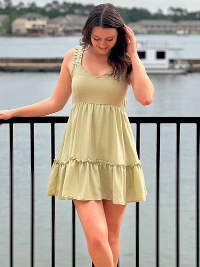 Megan in olive dress smiling looking at dress