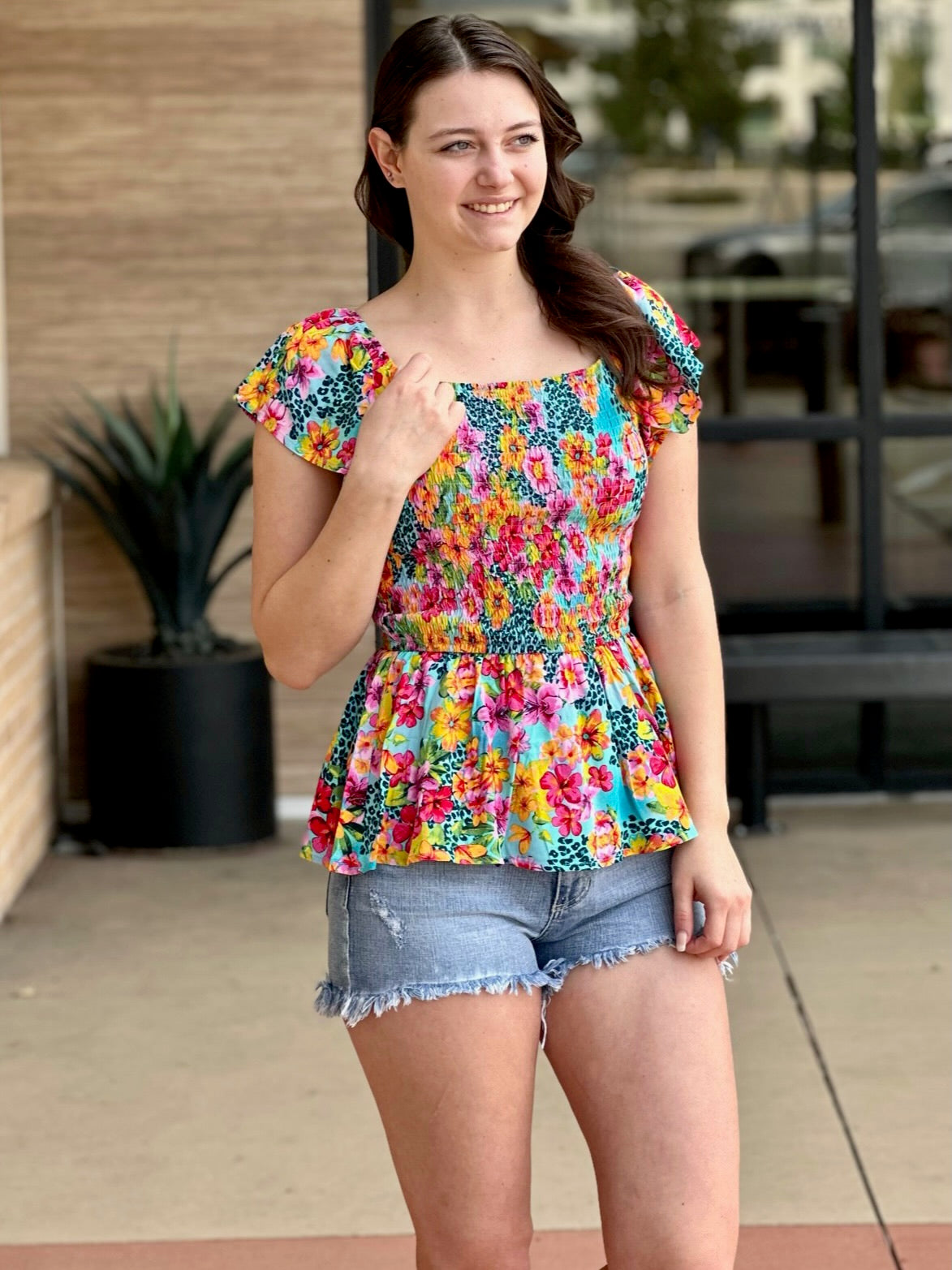 Megan in multi floral blouse hand on blouse