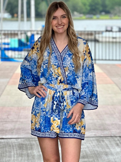 Lexi in blue romper hand on hip