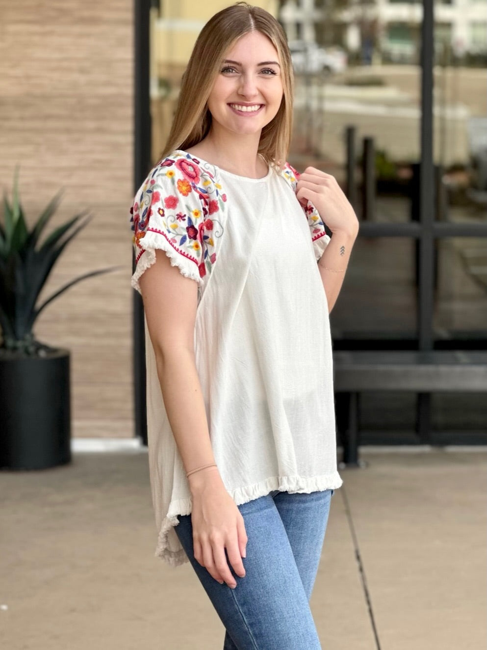 Lexi in off white top side view holding sleeve
