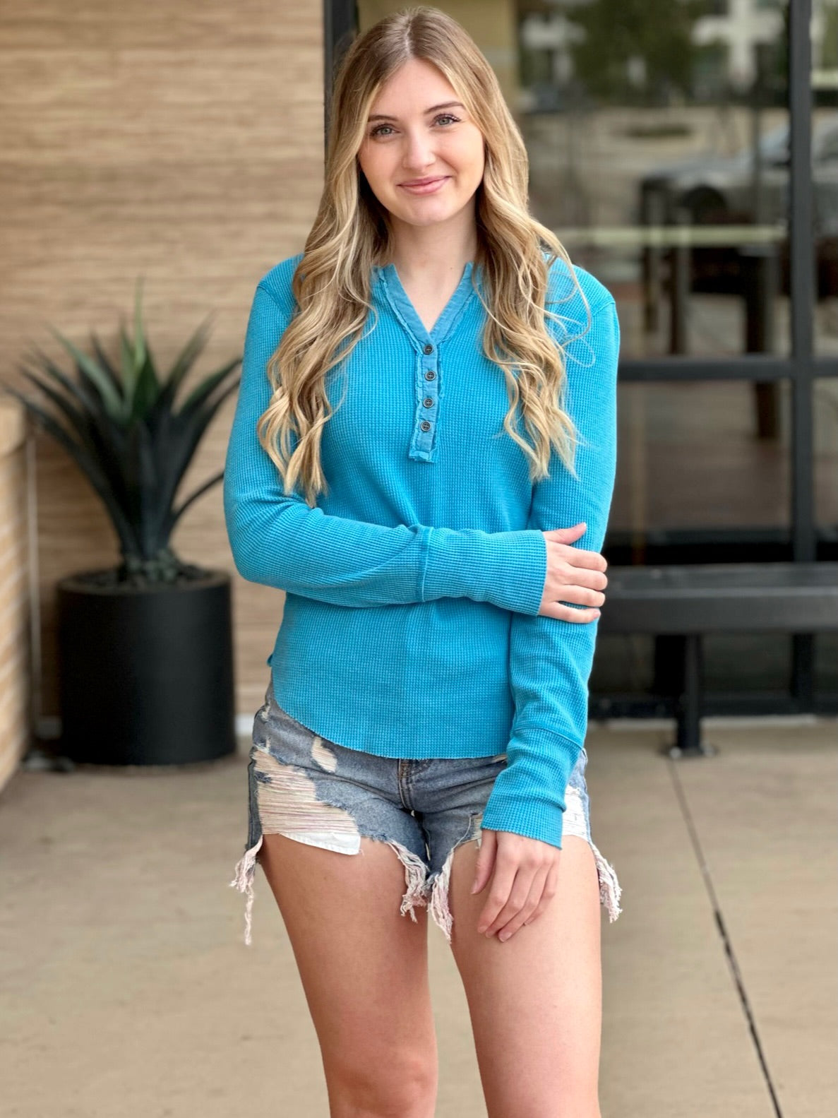 Lexi in turquoise henley front view hand on arm