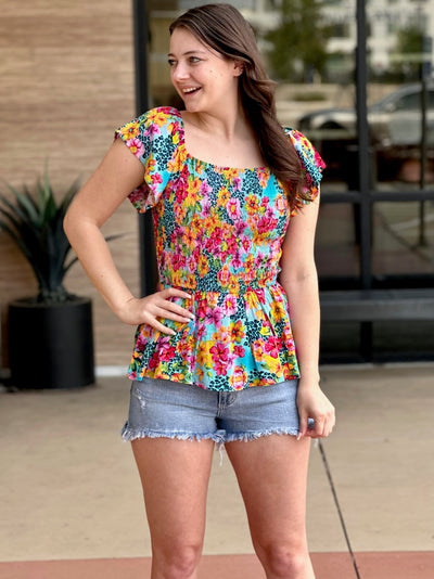 Megan in multi floral blouse hand on hip
