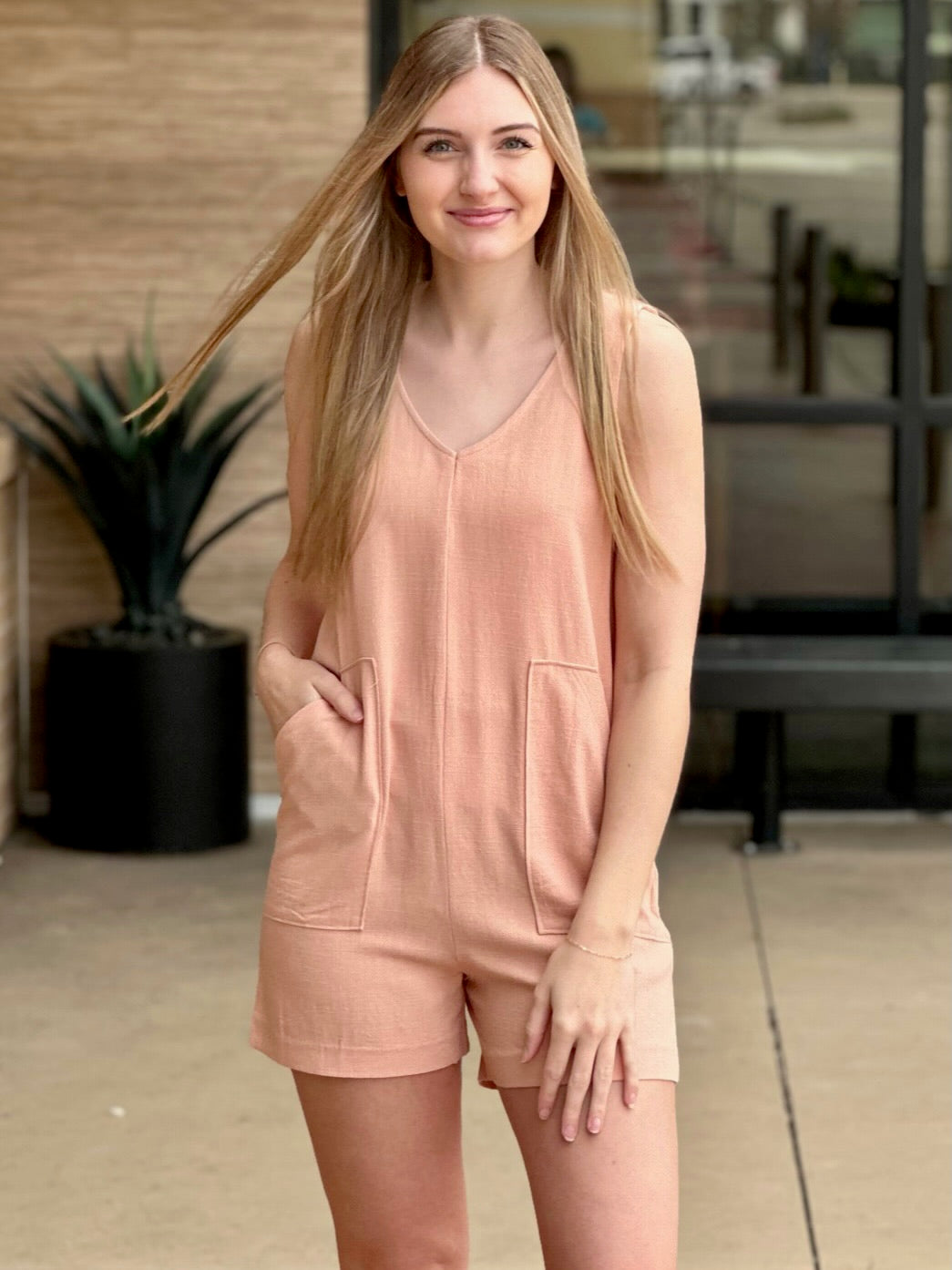 Lexi in tropical peach romper front view one hand in pocket